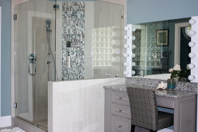 This is an example of a large classic ensuite bathroom in Other with raised-panel cabinets, grey cabinets, grey tiles, blue walls, granite worktops, a corner shower, porcelain tiles, a hinged door, a freestanding bath, porcelain flooring, a submerged sink and grey floors.