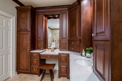 Mid-sized elegant master travertine floor bathroom photo in Atlanta with raised-panel cabinets, medium tone wood cabinets, a two-piece toilet, beige walls, an undermount sink and quartz countertops