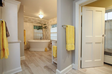 This is an example of an expansive traditional ensuite bathroom in Milwaukee with freestanding cabinets, white cabinets, a freestanding bath, a corner shower, a two-piece toilet, beige tiles, ceramic tiles, grey walls, porcelain flooring, a submerged sink, engineered stone worktops, grey floors and a hinged door.