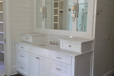Modelo de cuarto de baño principal tradicional renovado con armarios tipo mueble, puertas de armario blancas, suelo de madera oscura y encimera de mármol