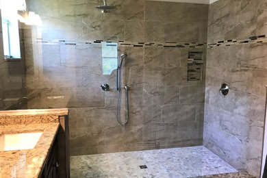 Example of a mid-sized trendy master beige tile open shower design in Tampa with recessed-panel cabinets, brown cabinets, an undermount sink, quartz countertops and multicolored countertops
