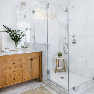 Mid-sized transitional master white tile and mosaic tile marble floor and gray floor corner shower photo in Austin with furniture-like cabinets, light wood cabinets, an undermount sink, marble countertops, a hinged shower door and white countertops