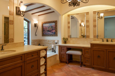 Large tuscan master beige tile and limestone tile porcelain tile, orange floor, double-sink and exposed beam bathroom photo in San Francisco with recessed-panel cabinets, medium tone wood cabinets, an undermount tub, a bidet, beige walls, an undermount sink, quartz countertops, a hinged shower door, beige countertops and a built-in vanity