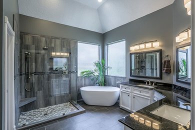 Freestanding bathtub - huge master gray tile and porcelain tile porcelain tile freestanding bathtub idea in Houston with recessed-panel cabinets, white cabinets, gray walls, an undermount sink and granite countertops