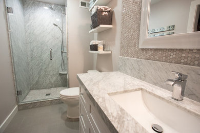 Стильный дизайн: главная ванная комната среднего размера в современном стиле с фасадами в стиле шейкер, белыми фасадами, накладной ванной, угловым душем, унитазом-моноблоком, серой плиткой, керамогранитной плиткой, серыми стенами, полом из керамогранита, врезной раковиной, мраморной столешницей, серым полом и душем с распашными дверями - последний тренд