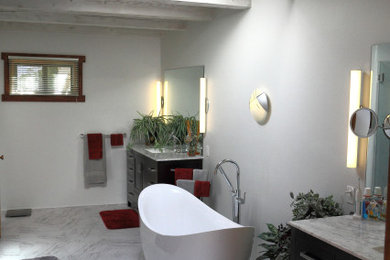 Photo of a large contemporary bathroom with shaker cabinets, dark wood cabinets, a freestanding bath, a corner shower, a two-piece toilet, grey tiles, ceramic tiles, grey walls, vinyl flooring, a submerged sink, marble worktops, grey floors, a hinged door and grey worktops.