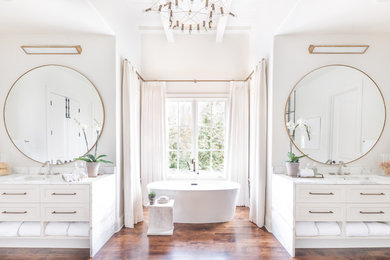 Transitional master dark wood floor and brown floor freestanding bathtub photo in Nashville with shaker cabinets, white cabinets, white walls, an undermount sink and white countertops
