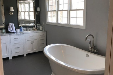 Exemple d'une salle de bain principale moderne de taille moyenne avec un placard à porte shaker, des portes de placard blanches, une baignoire indépendante, une douche d'angle, un carrelage beige, un mur gris, un sol en ardoise, un lavabo encastré, un plan de toilette en granite, un sol gris, une cabine de douche à porte battante et un plan de toilette gris.
