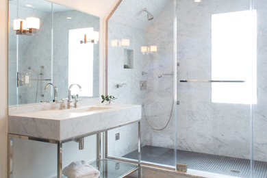 Example of a large transitional master gray tile and marble tile medium tone wood floor and brown floor bathroom design in New York with a console sink, open cabinets, white cabinets, marble countertops, white walls and a hinged shower door