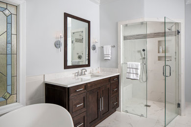 Idée de décoration pour une grande salle de bain principale tradition en bois clair avec un placard avec porte à panneau encastré, une baignoire indépendante, une douche d'angle, un carrelage gris, un carrelage blanc, des carreaux de porcelaine, un mur gris, un sol en carrelage de porcelaine, un lavabo encastré, un sol blanc et une cabine de douche à porte battante.