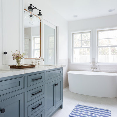 Inspiration for a mid-sized contemporary master beige tile and subway tile porcelain tile and white floor bathroom remodel in Los Angeles with an undermount sink, shaker cabinets, blue cabinets, white walls, a hinged shower door, beige countertops and marble countertops