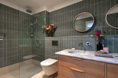 Large contemporary ensuite half tiled bathroom in Brisbane with freestanding cabinets, light wood cabinets, a walk-in shower, green tiles, ceramic tiles, white walls, cement flooring, a submerged sink, marble worktops, beige floors, an open shower, white worktops and a wall mounted toilet.