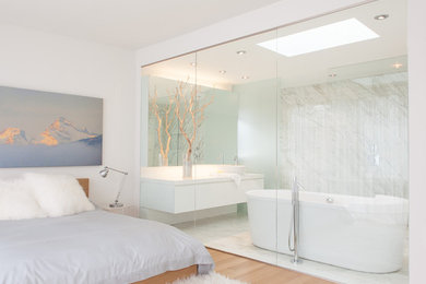 Imagen de cuarto de baño contemporáneo con lavabo sobreencimera, armarios con paneles lisos, puertas de armario blancas, bañera exenta y baldosas y/o azulejos blancos