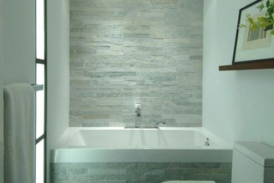 Inspiration for a modern bathroom in Los Angeles with an alcove bath, grey tiles, stone tiles, white walls and grey floors.