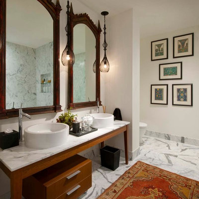 Freestanding bathtub - large eclectic stone slab marble floor freestanding bathtub idea in Dallas with a vessel sink, medium tone wood cabinets, marble countertops, a one-piece toilet, white walls and flat-panel cabinets