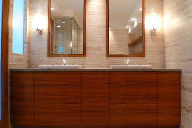 シカゴにあるコンテンポラリースタイルのおしゃれな浴室 (オーバーカウンターシンク、フラットパネル扉のキャビネット、中間色木目調キャビネット、クオーツストーンの洗面台、アルコーブ型シャワー、分離型トイレ、ベージュのタイル、石タイル) の写真