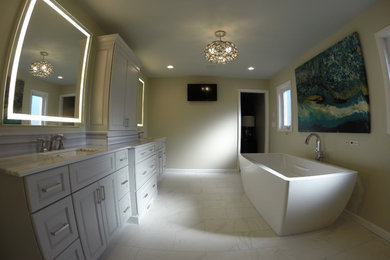 Diseño de cuarto de baño principal actual grande con puertas de armario blancas, bañera exenta, baldosas y/o azulejos blancos y suelo de mármol