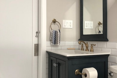 Photo of a small modern ensuite bathroom in Philadelphia with freestanding cabinets, blue cabinets, an alcove bath, a shower/bath combination, a two-piece toilet, white tiles, ceramic tiles, beige walls, ceramic flooring, an integrated sink, solid surface worktops, beige floors, a shower curtain and white worktops.