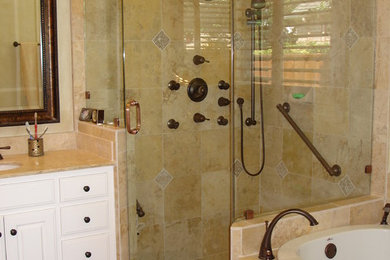 Cette image montre une salle de bain principale de taille moyenne avec un lavabo encastré, un placard avec porte à panneau surélevé, des portes de placard blanches, un plan de toilette en calcaire, une baignoire posée, une douche d'angle, un carrelage de pierre et un sol en travertin.