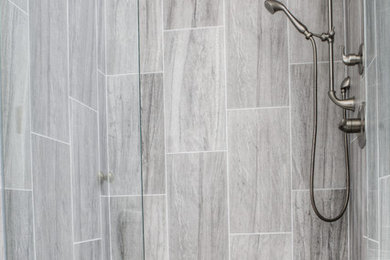 Example of a trendy master gray tile and ceramic tile ceramic tile alcove shower design in Other with recessed-panel cabinets, dark wood cabinets, gray walls, an undermount sink and quartz countertops