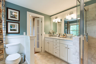 Medium sized classic ensuite bathroom in Philadelphia with a submerged sink, raised-panel cabinets, white cabinets, marble worktops, a two-piece toilet, beige tiles, ceramic tiles, green walls, a corner shower, ceramic flooring, beige floors and a hinged door.
