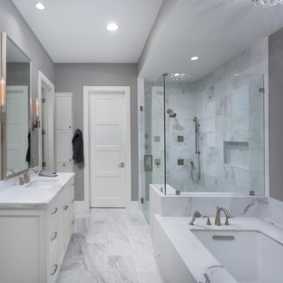Example of a large transitional master gray tile and marble tile marble floor, gray floor and single-sink bathroom design in Austin with shaker cabinets, white cabinets, gray walls, an undermount sink, an undermount tub, marble countertops, a hinged shower door, white countertops and a built-in vanity