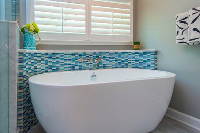 Свежая идея для дизайна: ванная комната в стиле неоклассика (современная классика) с отдельно стоящей ванной, синей плиткой, стеклянной плиткой, серыми стенами и полом из керамогранита - отличное фото интерьера