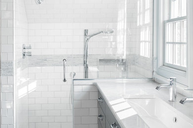 ニューヨークにあるトラディショナルスタイルのおしゃれな浴室 (アンダーカウンター洗面器、フラットパネル扉のキャビネット、グレーのキャビネット、アルコーブ型シャワー、白いタイル、サブウェイタイル) の写真