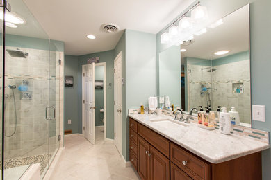 This is an example of a medium sized traditional ensuite bathroom in Philadelphia with a submerged sink, raised-panel cabinets, marble worktops, green walls, ceramic flooring, dark wood cabinets, a built-in bath, a walk-in shower, beige tiles, ceramic tiles, beige floors and a hinged door.