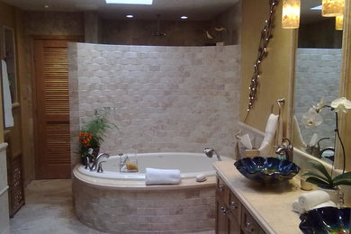 Inspiration for a large contemporary master beige tile and cement tile ceramic tile bathroom remodel in Albuquerque with a vessel sink, glass-front cabinets, medium tone wood cabinets, limestone countertops, a two-piece toilet and yellow walls