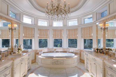 Immagine di una grande stanza da bagno padronale minimalista con lavabo da incasso, consolle stile comò, ante in legno chiaro, top in onice, vasca da incasso, piastrelle beige, lastra di pietra, pareti beige e pavimento in marmo