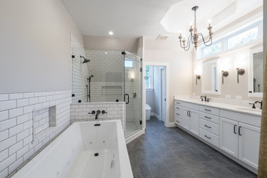 This is an example of a medium sized classic ensuite bathroom in Other with recessed-panel cabinets, white cabinets, a freestanding bath, a corner shower, a one-piece toilet, white tiles, metro tiles, grey walls, ceramic flooring, a submerged sink, engineered stone worktops, grey floors, a hinged door and white worktops.