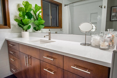 Cette photo montre une petite salle de bain moderne en bois brun pour enfant avec un placard à porte plane, une baignoire en alcôve, un combiné douche/baignoire, WC séparés, un carrelage blanc, des carreaux de céramique, un mur blanc, un sol en carrelage de céramique, un lavabo encastré, un plan de toilette en quartz modifié, un sol noir, une cabine de douche avec un rideau, un plan de toilette blanc, meuble simple vasque et meuble-lavabo encastré.