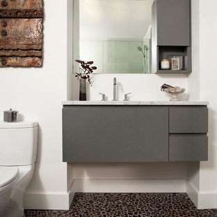 Bathroom - mid-sized contemporary pebble tile floor bathroom idea in Denver with white walls, a one-piece toilet, an undermount sink, flat-panel cabinets, gray cabinets, marble countertops and white countertops