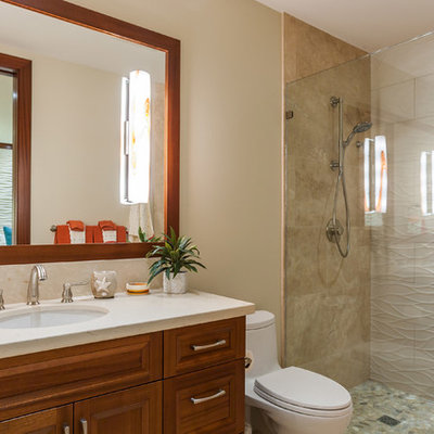 Inspiration for a tropical 3/4 beige tile alcove shower remodel in Hawaii with raised-panel cabinets, medium tone wood cabinets, a one-piece toilet, beige walls, an undermount sink and a hinged shower door
