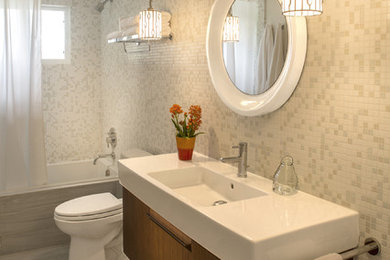 Example of a mid-sized trendy white tile porcelain tile bathroom design in Other with flat-panel cabinets, medium tone wood cabinets, a one-piece toilet, white walls and an integrated sink