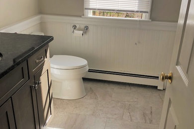 Mid-sized elegant master porcelain tile and beige floor bathroom photo in Boston with shaker cabinets, medium tone wood cabinets, a two-piece toilet, beige walls, an undermount sink, granite countertops and black countertops