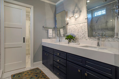 Пример оригинального дизайна: главная ванная комната среднего размера в стиле неоклассика (современная классика) с фасадами с выступающей филенкой, синими фасадами, двойным душем, белой плиткой, мраморной плиткой, серыми стенами, полом из керамогранита, врезной раковиной, столешницей из искусственного кварца, белым полом, душем с распашными дверями и белой столешницей
