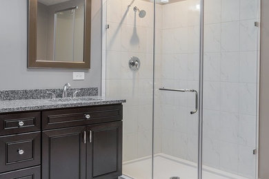 Example of a mid-sized transitional master white tile and porcelain tile porcelain tile and multicolored floor bathroom design in Chicago with shaker cabinets, black cabinets, an undermount sink, granite countertops, a hinged shower door, multicolored countertops and gray walls