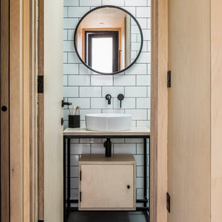 This is an example of a scandinavian bathroom in Oxfordshire with flat-panel cabinets, light wood cabinets, white tile, subway tile, white walls, concrete floors, a vessel sink, wood benchtops, grey floor and beige benchtops.