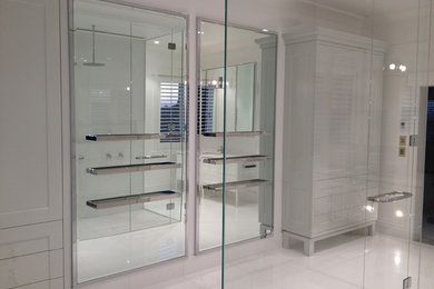 Expansive modern ensuite bathroom in Melbourne with recessed-panel cabinets, a submerged sink, grey cabinets, marble worktops, a double shower, a wall mounted toilet, white tiles, stone tiles, white walls and marble flooring.