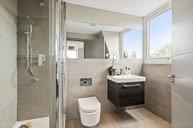 Inspiration pour une petite salle de bain design avec un placard à porte plane, des portes de placard noires, WC suspendus, un carrelage gris, un mur gris, un sol gris, une douche d'angle, un lavabo intégré et un plan de toilette blanc.
