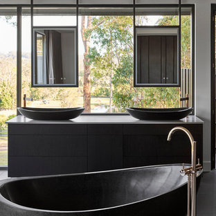 Design ideas for a modern master bathroom in Sunshine Coast with flat-panel cabinets, black cabinets, a freestanding tub, a vessel sink, grey floor, grey benchtops and a double vanity.