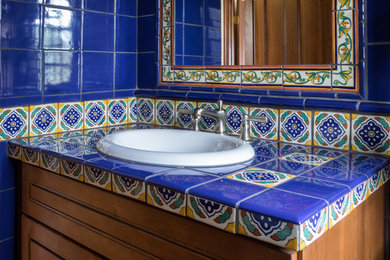 Bathroom - mid-sized southwestern 3/4 blue tile and ceramic tile bathroom idea in Boston with shaker cabinets, medium tone wood cabinets, a drop-in sink and tile countertops