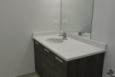Ejemplo de cuarto de baño actual de tamaño medio con armarios con paneles lisos, puertas de armario de madera en tonos medios y encimera de cuarzo compacto