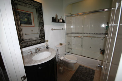 グランドラピッズにある中くらいなトラディショナルスタイルのおしゃれな浴室 (アルコーブ型浴槽、アルコーブ型シャワー、一体型トイレ	、白いタイル、セラミックタイル、白い壁、磁器タイルの床、アンダーカウンター洗面器、大理石の洗面台) の写真