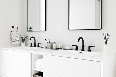 Mid-sized trendy master white tile and subway tile porcelain tile and black floor drop-in bathtub photo in Chicago with flat-panel cabinets, white cabinets, a two-piece toilet, an integrated sink, solid surface countertops, white countertops and white walls