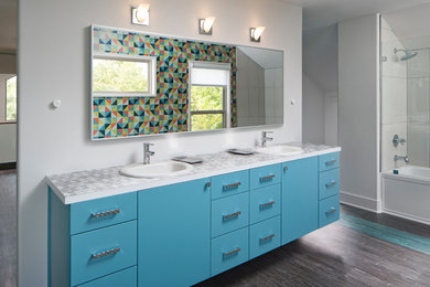 Inspiration for a mid-sized 1950s white tile laminate floor and brown floor tub/shower combo remodel in Dallas with flat-panel cabinets, blue cabinets, white walls, a drop-in sink and laminate countertops