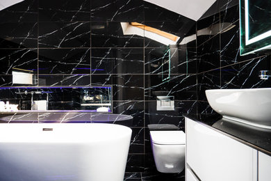 Inspiration for a medium sized contemporary family bathroom in Other with flat-panel cabinets, white cabinets, a freestanding bath, a walk-in shower, a wall mounted toilet, black and white tiles, porcelain tiles, black walls, porcelain flooring, a vessel sink, glass worktops, black floors, an open shower, black worktops, a wall niche, double sinks, a floating vanity unit and a vaulted ceiling.