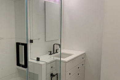 Идея дизайна: маленькая главная ванная комната в стиле модернизм с плоскими фасадами, белыми фасадами, угловым душем, унитазом-моноблоком, белой плиткой, стеклянной плиткой, белыми стенами, полом из керамогранита, врезной раковиной, стеклянной столешницей, белым полом, душем с распашными дверями, белой столешницей, нишей, тумбой под одну раковину и встроенной тумбой для на участке и в саду